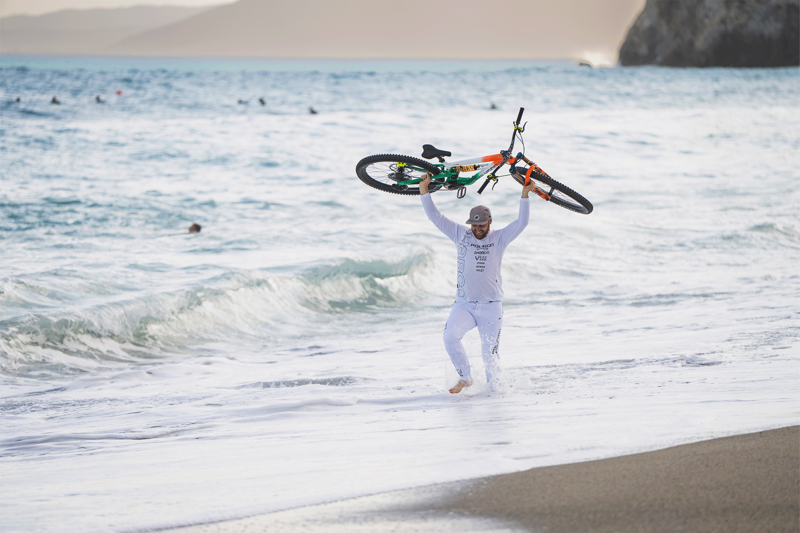 BikeYoke Athlet trägt sein Bike lachend aus dem Meer